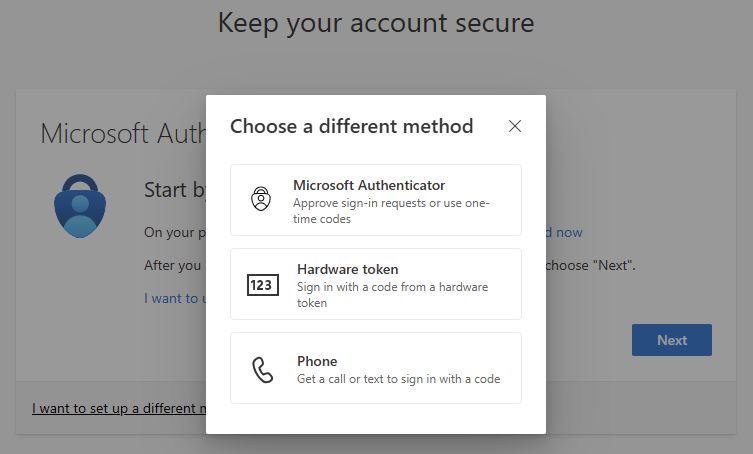 A pop-up window titled 'Choose a different method' offers three options for account security: 'Microsoft Authenticator' to approve sign-in requests or use one-time codes, 'Hardware token' to sign in with a code from a hardware token, and 'Phone' to get a call or text to sign in with a code. The background shows part of a Microsoft Authenticator setup screen with a 'Next' button."